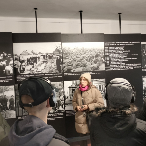 Młodzież zasłuchana w opowieści przewodnika na temat selekcji po przybyciu transportu więźniów do obozu w Auschwitz