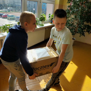 Uczniowie z klasy 5b niosą paczkę dla uczniów przebywających na Ukrainie