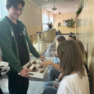 Przewodniczący Samorządu Uczniowskiego podczas przerwy częstuje ciastem czekoladowym